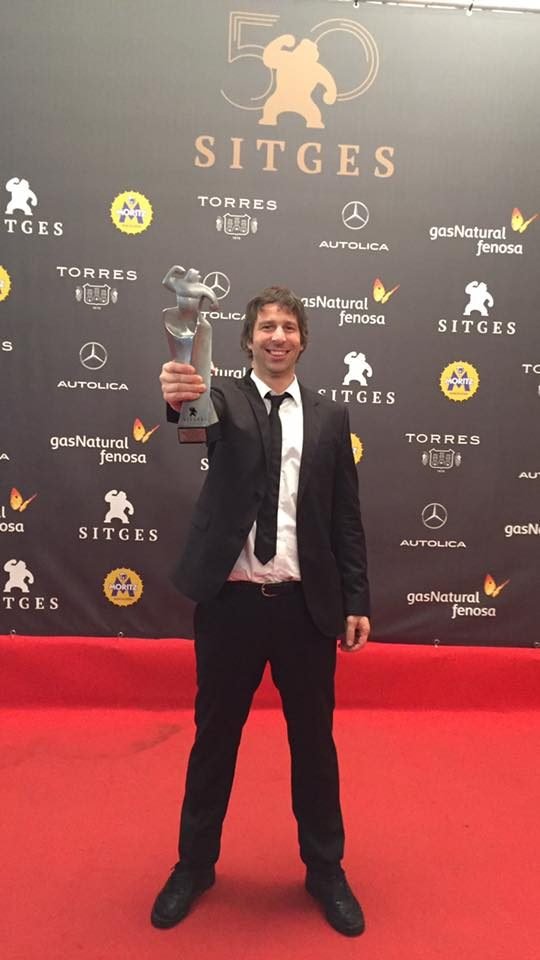 Hernán Aguilar holding an award on the red carpet at the Sitges Film Festival